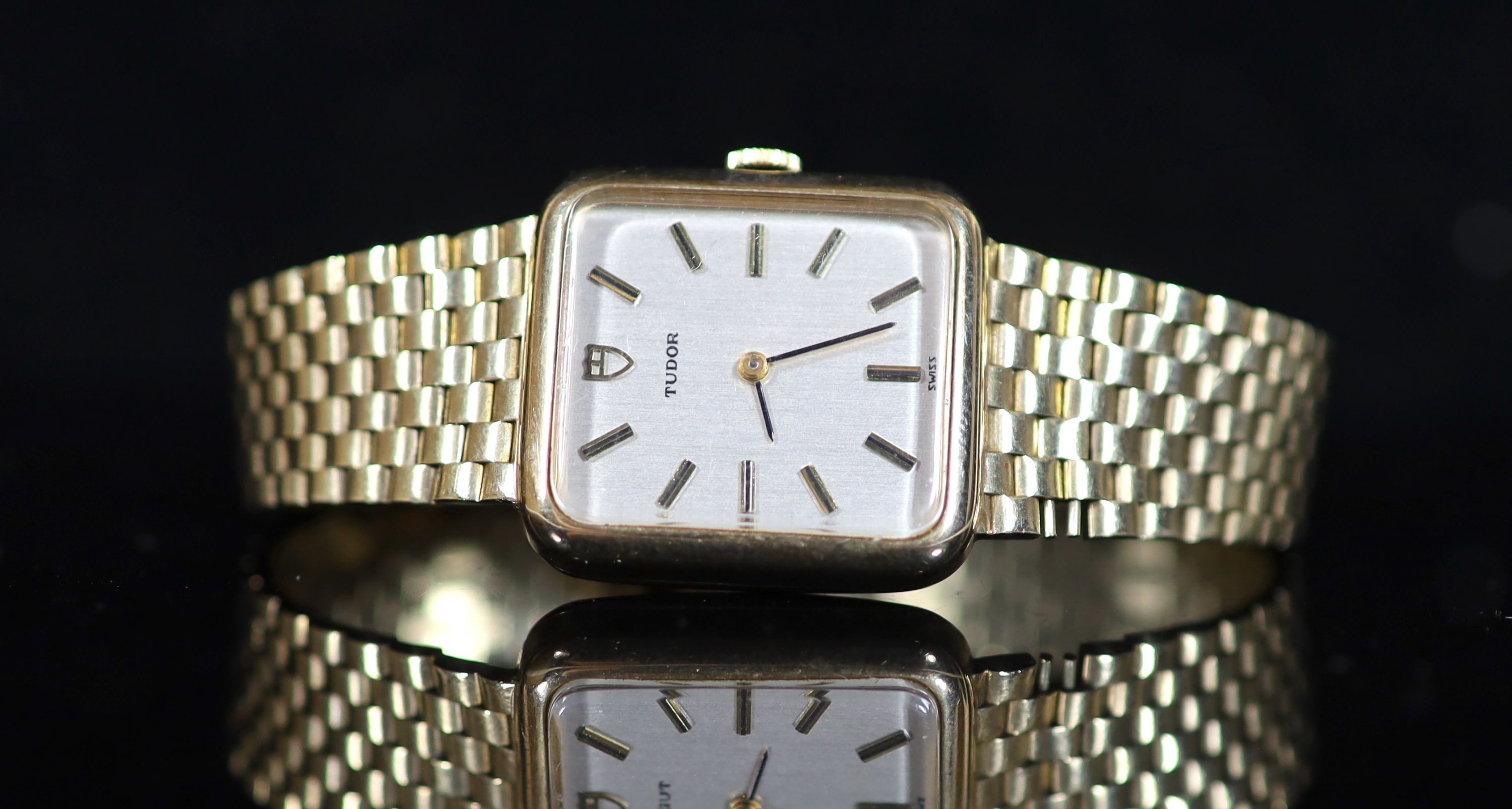 A lady's 1980's 9ct gold Tudor manual wind rectangular dial wrist watch, on an integral 9ct gold brick link bracelet